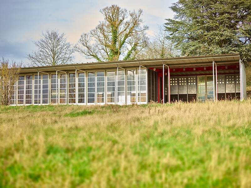 The school in its meadow, the south façade and the covered play area at the far end